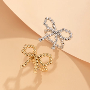 Detailed view of beaded metal bow rings in gold and silver over geometric background