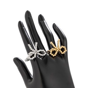 Close-up of golden and silver metal bow rings with pearl bead texture on a model hand