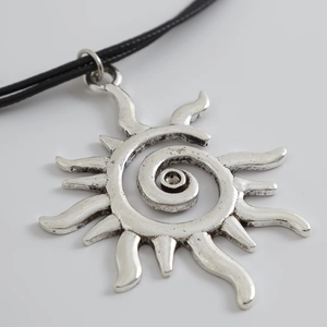 Detalle del colgante de sol plateado bohemio con textura de espiral en cordón negro