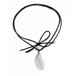 Detalle de colgante de plata irregular con textura rayada y cordón negro con lazo