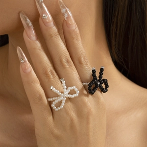 Detail of bow-shaped pearl and black beaded rings with rhinestones on hand