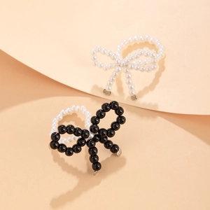 Macro detail of elegant beaded bow rings featuring classic white and black pearl textures