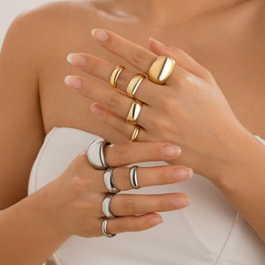Close-up of minimalist chunky dome rings in gold and silver finish on a model hand