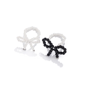 Detail of beaded bow ring set featuring white and black pearls with metal connectors