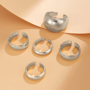 Detailed view of 5-piece silver lava style metal rings set on warm beige texture