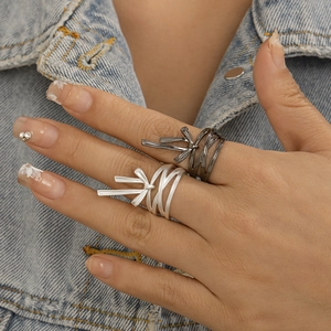 Detail of matte silver and gunmetal black bow-shaped wrap rings on a model