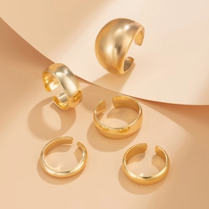 Detailed view of five adjustable gold rings with irregular lava texture and polished finish
