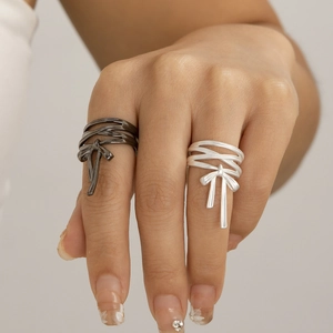 Close-up of multilayer silver and gun-black bow rings with flowing metallic tassels