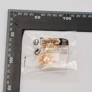 Detail of gold beaded earrings in original packaging with a measuring scale