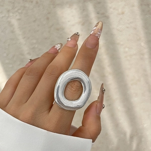 Minimalist silver irregular oval ring with brushed metal texture worn by a model