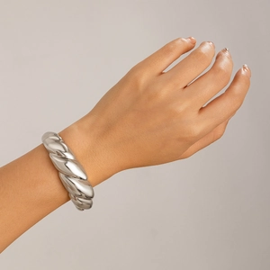 Close-up of polished silver twisted cuff bracelet on a model wrist in a minimalist style