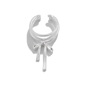 Macro detail of silver ribbon bow ring with fluid lines and metallic tassel pendants