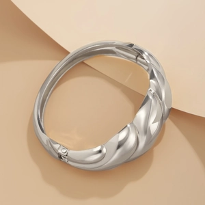 Close-up of silver metal chunky bangle with twisted croissant pattern and hinged closure