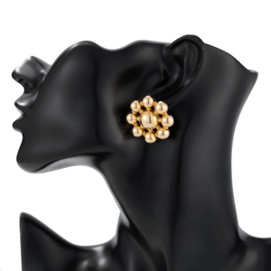 Detail of gold beaded flower earrings on a black mannequin, geometric metal style