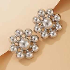 Close-up of silver geometric beaded flower earrings with high-polish metallic finish