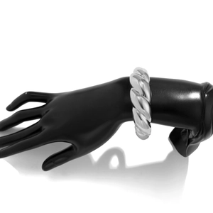 Macro detail of high-polish silver twisted chunky metal cuff bracelet on hand model