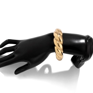 Detailed close-up of chunky gold-tone twisted rope cuff bracelet on a display stand