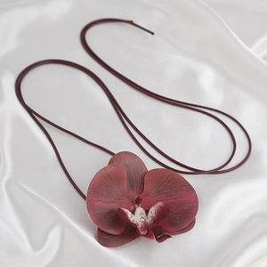 Detail eines burgunderfarbenen Orchideen-Chokers mit Blütenblattstruktur auf weißer Seide