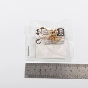 Detailansicht eines goldenen geometrischen Rings im Beutel neben einem Messlineal