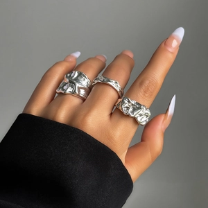 Detailaufnahme von drei unregelmäßigen Ringen im flüssigen Metallstil an den Fingern