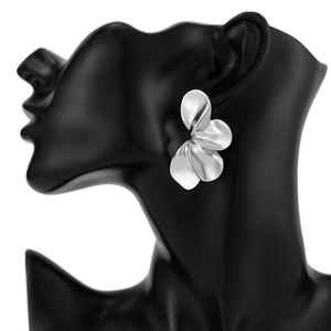 Detailopname van zilveren metalen bladoorbellen op een zwart model met modern bloemdesign