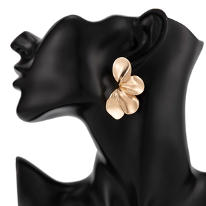 Detail van matgouden bloemblaadjes oorbellen op een zwarte buste voor een elegante look