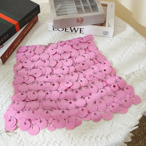 Detailed close-up of pink sequin mini skirt with metallic rings on a textured surface
