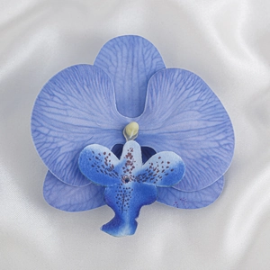 Detailaufnahme einer blauen Orchideen-Halskette auf elegantem weißem Seidenhintergrund