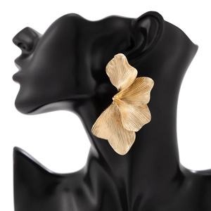 Macro zijaanzicht van gelaagde gouden bloemoorbellen met bloembladtextuur op een mannequin