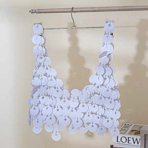Detailed close-up of white sequin halter top with silver metal rings on a hanger