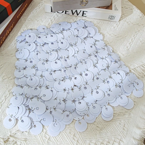 Detail of white sequin body chain showing metallic rings and layered disk texture
