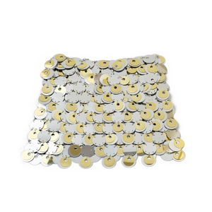 Dettaglio ravvicinato di paillettes oro e argento sovrapposte con anelli metallici