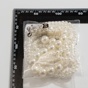 Detalle de gargantilla multicapa de perlas sintéticas en bolsa transparente ecológica