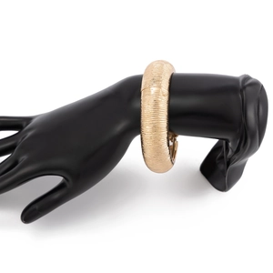 Detailopname van gouden brede manchetarmband met verticale strepen op zwart handmodel
