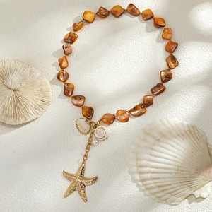 Detail of beach ocean necklace with orange beads, golden starfish and sea shell charms