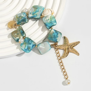 Detail of ocean-themed bracelet with blue mother-of-pearl beads and gold starfish charm