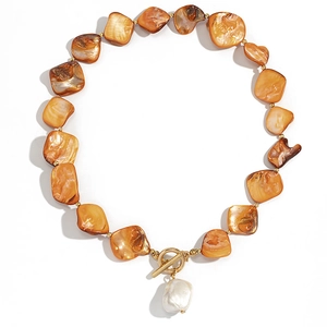Detail of amber shell beads necklace with baroque pearl pendant and gold toggle clasp