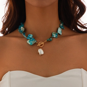 Detail of turquoise stone necklace with baroque pearl pendant and golden toggle clasp