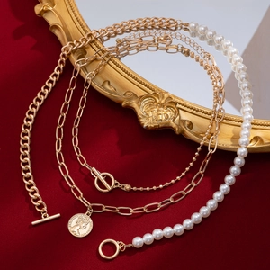 Detail of layered gold metal chains with pearls, coin pendant, and OT toggle clasp