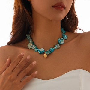 Detailed close-up of blue shell beaded necklace with golden seashell pendant on neck