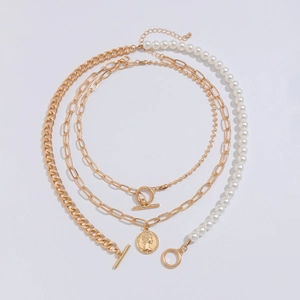 Layered gold chain necklace with white pearls and vintage coin pendant in concentric arrangement