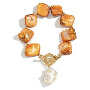 Detail of bohemian toggle clasp bracelet with orange resin blocks and baroque pearl charm