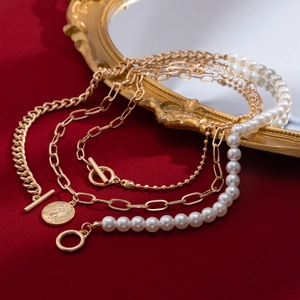 Detail of layered gold coin necklace with faux pearls and vintage Elizabeth II pendant