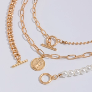 Detail of layered gold coin necklace with pearl chain and OT buckle closure