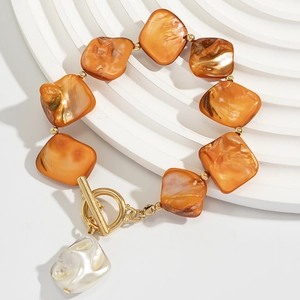 Detail of orange square beads bracelet with golden toggle clasp and baroque pearl charm