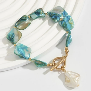 Detail of teal shell fragments and baroque pearl pendant on a gold OT buckle bracelet