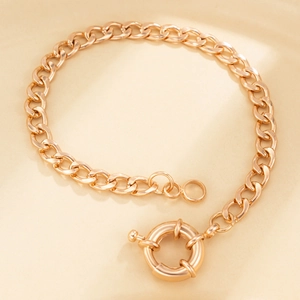 Close-up of golden chunky curb chain bracelet featuring a large round spring clasp