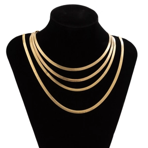 Detail of layered gold herringbone snake chain necklaces on a black velvet display