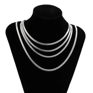 Detail of four layered silver herringbone chains on a black neck bust display