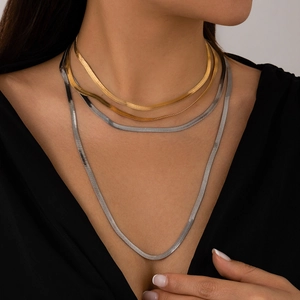 Close-up of layered gold and silver herringbone snake chains on female neck